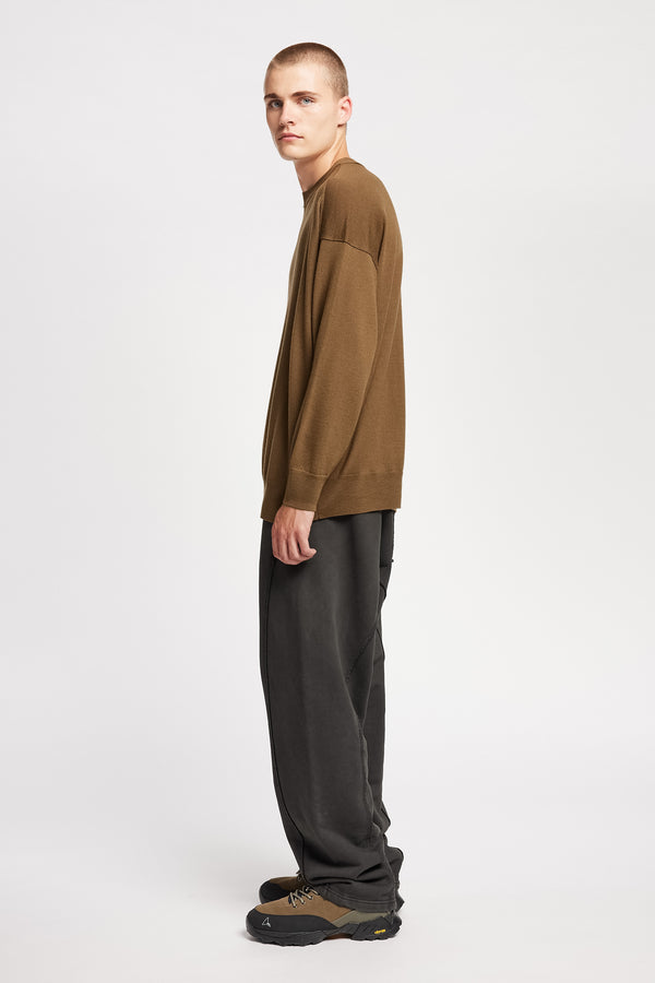 Side of Model wearing relaxed tapered fleece pants in Black pigment-dyed cotton with curved seam detailing and elastic waistband