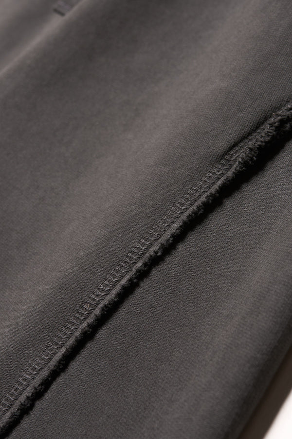 Close up fabric shot of Black pigment-dyed cotton with curved raw flatlock seam detailing