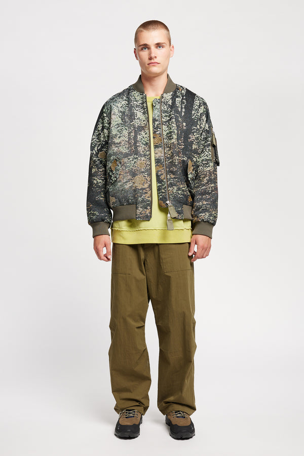 Men - Front of Unisex bomber jacket in Green Print woven jacquard with real tree camouflage, featuring dropped shoulders, ribbed trims, and full-length front zip.