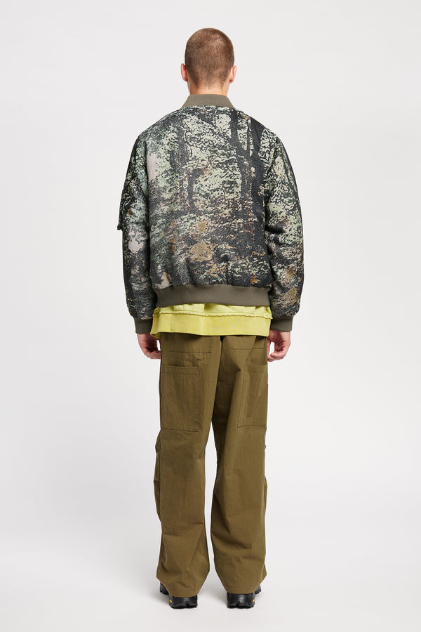 Men Back of Unisex bomber jacket in Green Print woven jacquard with real tree camouflage, featuring dropped shoulders, ribbed trims, and full-length front zip.