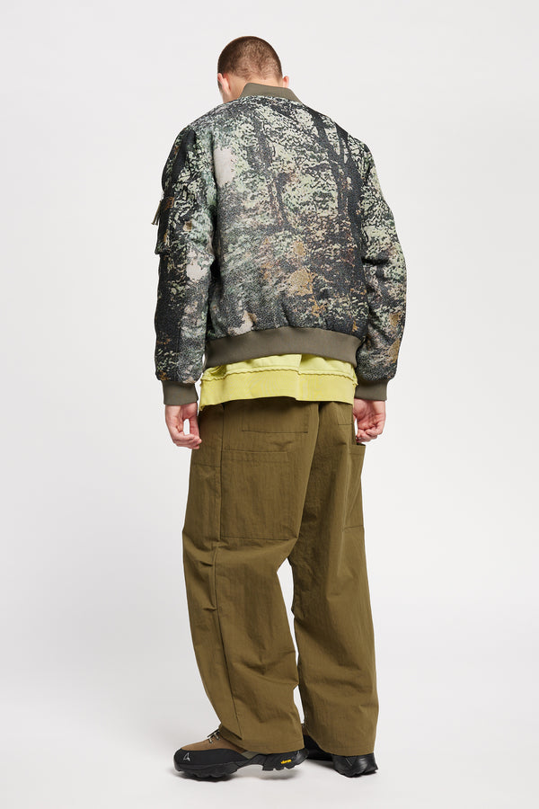 Men - Back of Unisex bomber jacket in Green Print woven jacquard with real tree camouflage, featuring dropped shoulders, ribbed trims, and full-length front zip.