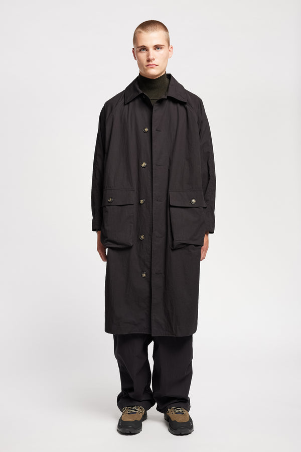 Front view of model wearing the venture trench coat in jet black. An oversized fit in cotton-nylon with structured collar and flap pockets