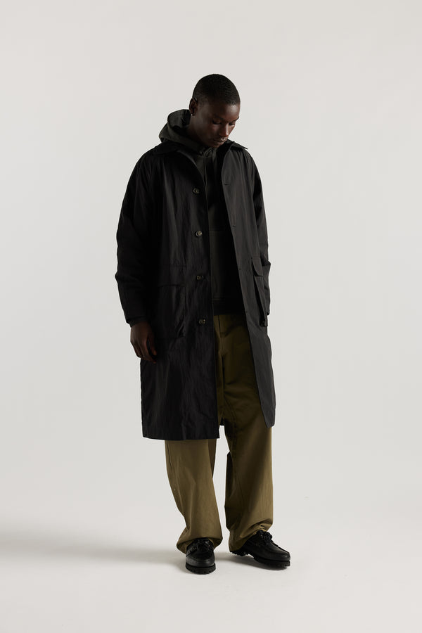 Front view of male model wearing the venture trench coat in jet black. An oversized fit in cotton-nylon with structured collar and flap pockets
