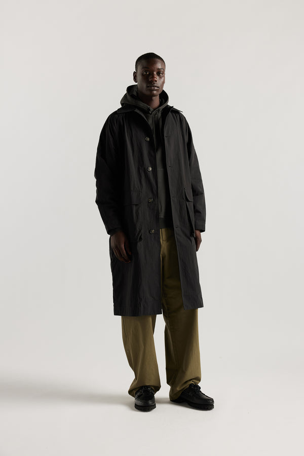 front view of male model wearing the venture trench coat in jet black. An oversized fit in cotton-nylon with structured collar and flap pockets
