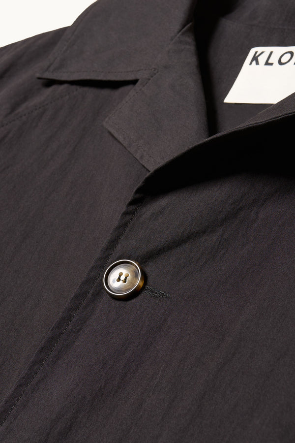 Close up collar detail shot of the Venture Trench in black,  an oversized fit in cotton-nylon with structured collar and flap pockets