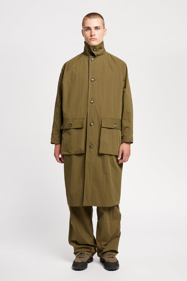 Front view of model wearing the venture trench coat in kelp green. An oversized fit in cotton-nylon with structured collar and flap pockets