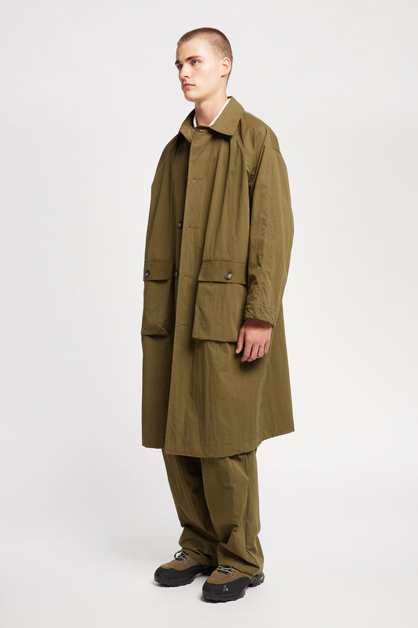 Front angle view of model wearing the venture trench coat in kelp green. An oversized fit in cotton-nylon with structured collar and flap pockets