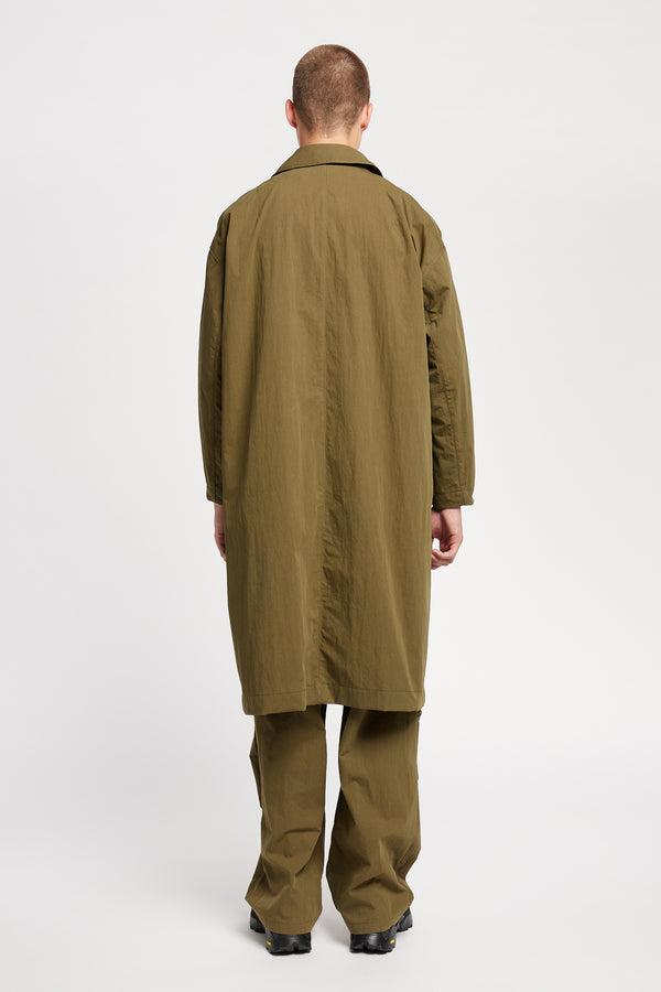Back view of model wearing the venture trench coat in kelp green. An oversized fit in cotton-nylon with structured collar and flap pockets
