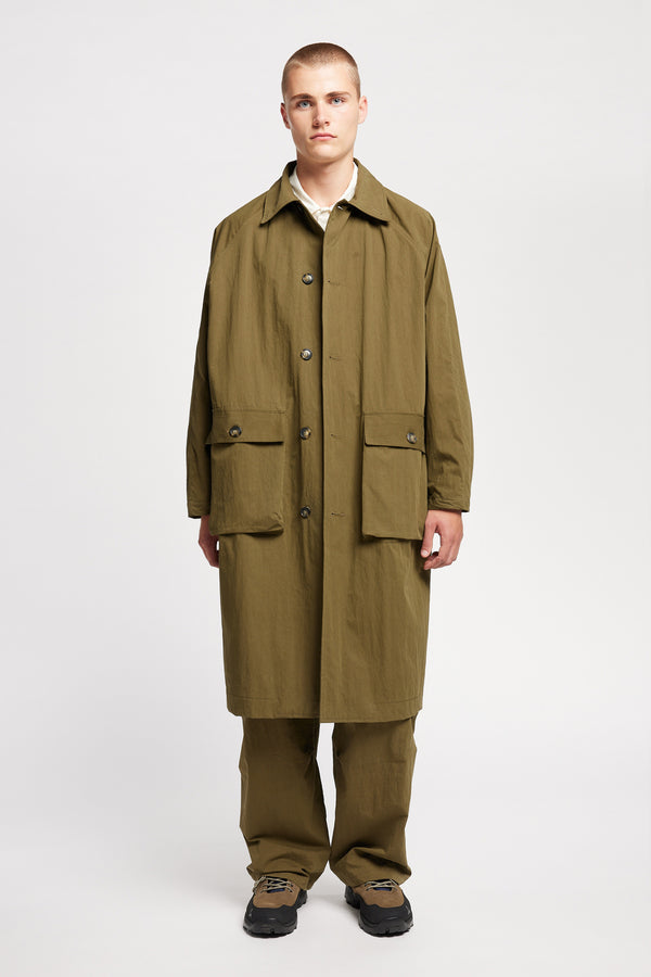 Front view of model wearing the venture trench coat in kelp green. An oversized fit in cotton-nylon with structured collar and flap pockets