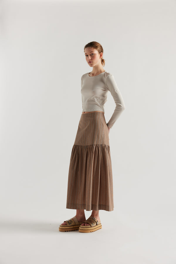 Front angle of Model in Clay Stripe Panelled cotton skirt with gathered full silhouette, wide yoke waist, and invisible back zip closure.