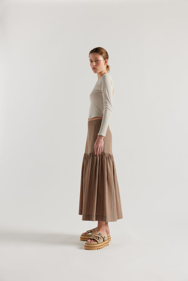 Side of Model in Clay Stripe Panelled cotton skirt with gathered full silhouette, wide yoke waist, and invisible back zip closure.