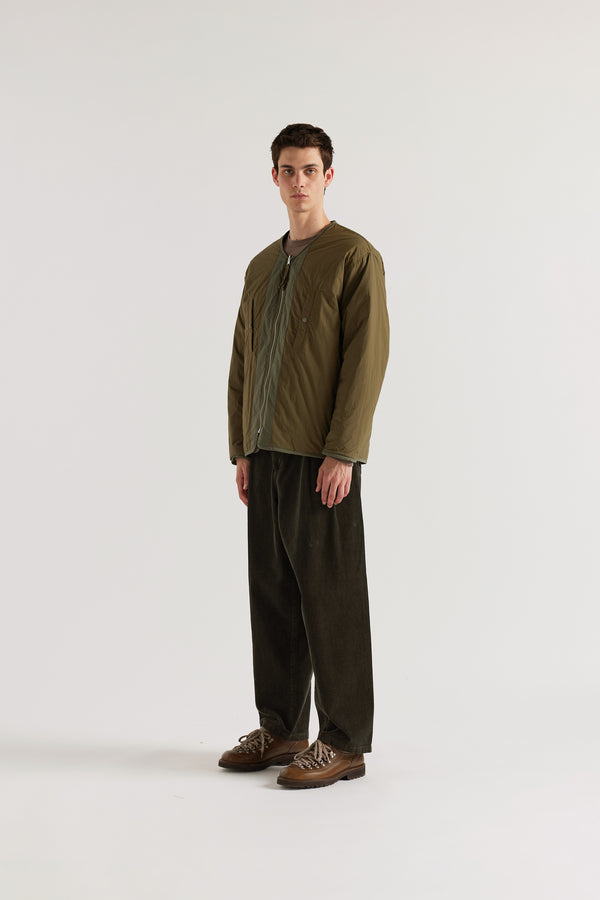 Front of the Olive Reversible recycled nylon jacket worn plain-side out, showing a clean minimalist finish with accessible pocket detail