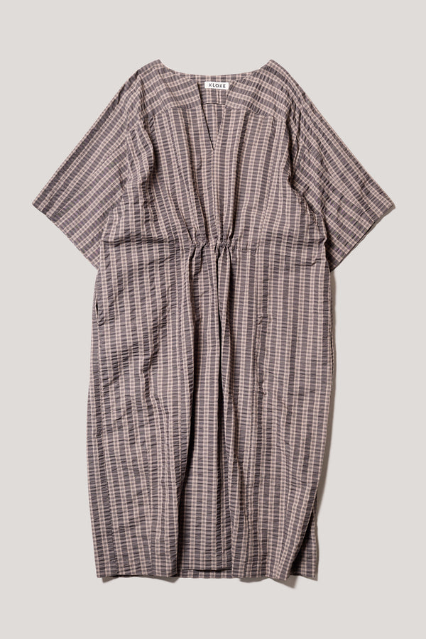 Flat front of the Origin Dress in gingham seersucker brown check. A relaxed silhouette with internal tie, clean neckline, and subtle underarm split detail.