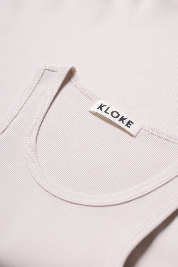Close up detail of the Wing tank in Bone, off white. A slim-fit 1x1 rib cotton tank with a slight racer neckline. A clean, minimal silhouette
