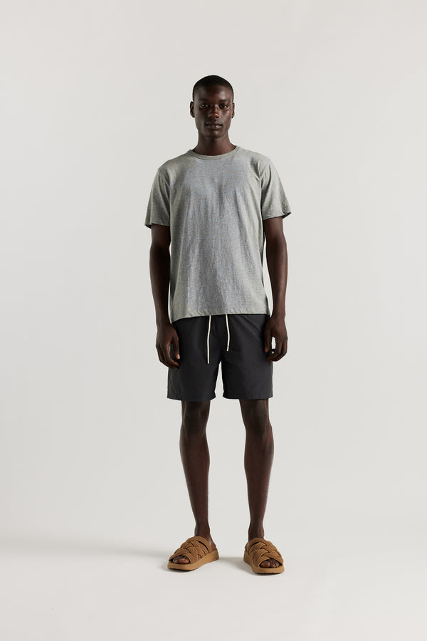 Front view of Ousmane wearing relaxed fit swim shorts in black with an elastic drawstring waist and functional pocket detailing.