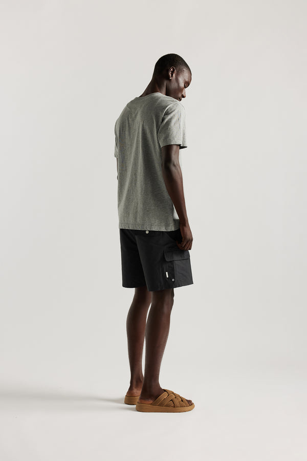back view of Ousmane wearing relaxed fit swim shorts in black with an elastic drawstring waist and functional pocket detailing.