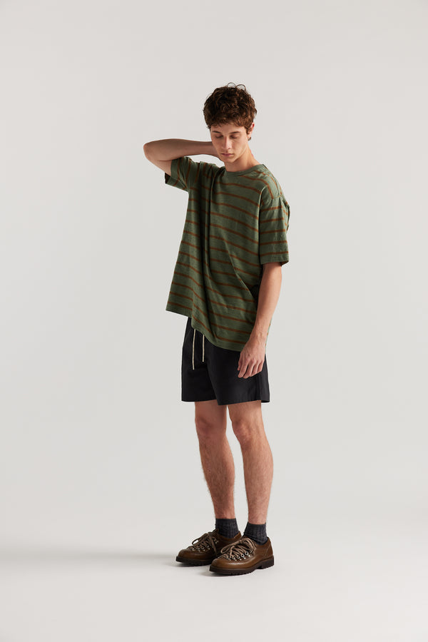 Front view of Luke wearing relaxed fit swim shorts in black with an elastic drawstring waist and functional pocket detailing.