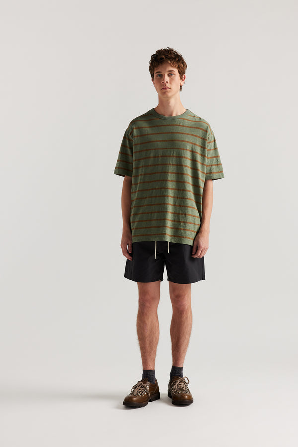 Front view of Luke wearing relaxed fit swim shorts in black with an elastic drawstring waist and functional pocket detailing.