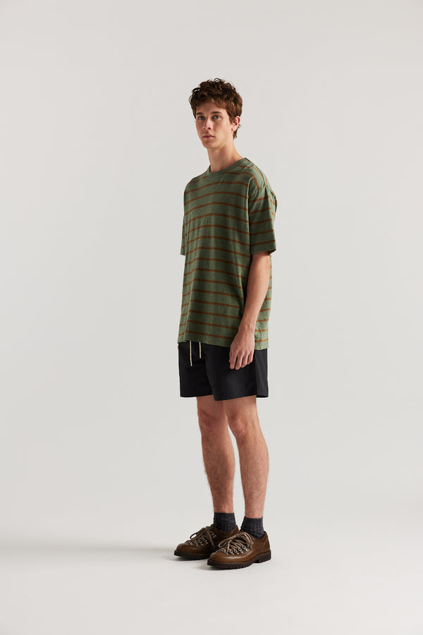 Front view of Luke wearing relaxed fit swim shorts in black with an elastic drawstring waist and functional pocket detailing.