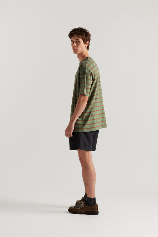 back view of Luke wearing relaxed fit swim shorts in black with an elastic drawstring waist and functional pocket detailing.