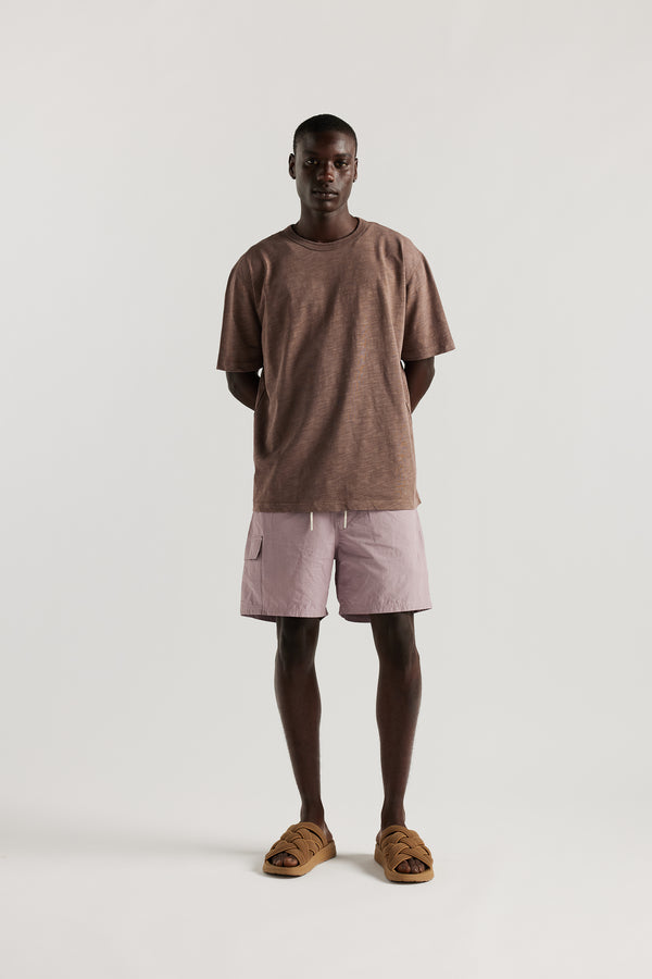 Front view of Male model wearing relaxed fit swim shorts in lilac with an elastic drawstring waist and functional pocket detailing.
