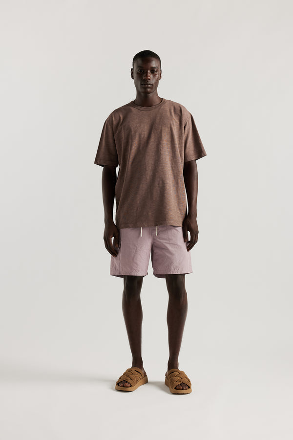 Front view of Male model wearing relaxed fit swim shorts in lilac with an elastic drawstring waist and functional pocket detailing.