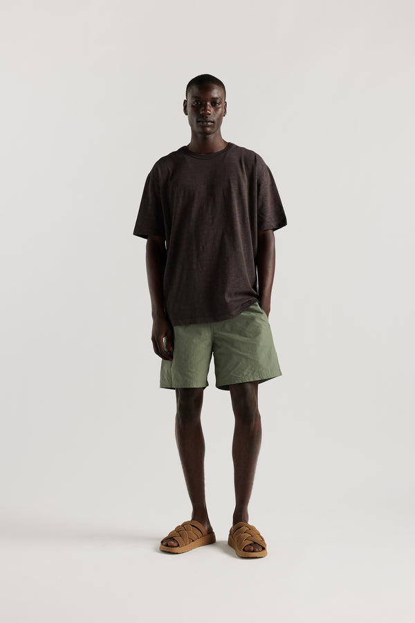 Front view of Male model wearing relaxed fit swim shorts in Olive green with an elastic drawstring waist and functional pocket detailing.