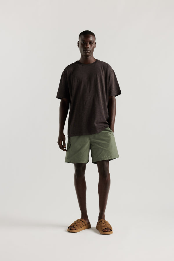 Front view of Male model wearing relaxed fit swim shorts in Olive green with an elastic drawstring waist and functional pocket detailing.