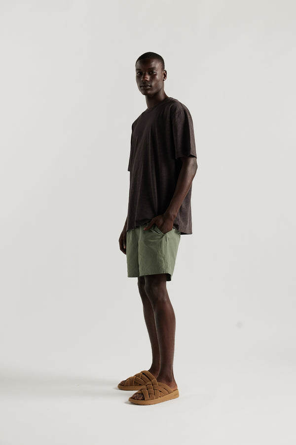 Front view of Male model wearing relaxed fit swim shorts in Olive green with an elastic drawstring waist and functional pocket detailing.