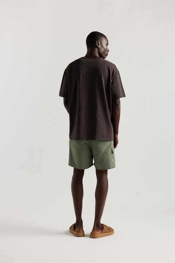 Back view of Male model wearing relaxed fit swim shorts in Olive green with an elastic drawstring waist and functional pocket detailing.