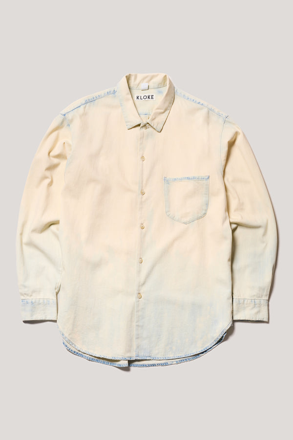 Flat Front Loose long sleeve Finite denim button-up shirt in Mid Blue Fade with Ecru Tint. Showing built-in collar, centre button placket, and chest patch pocket with rivet details.