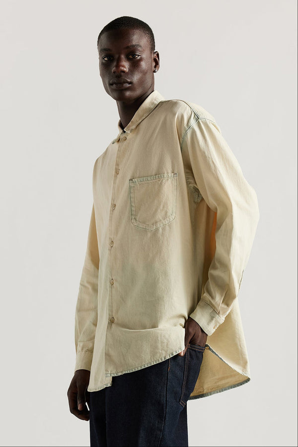 Front view of model in Mid blue Fade with Ecru tint Finite denim shirt showing rounded hem finished with bar tack detailing.