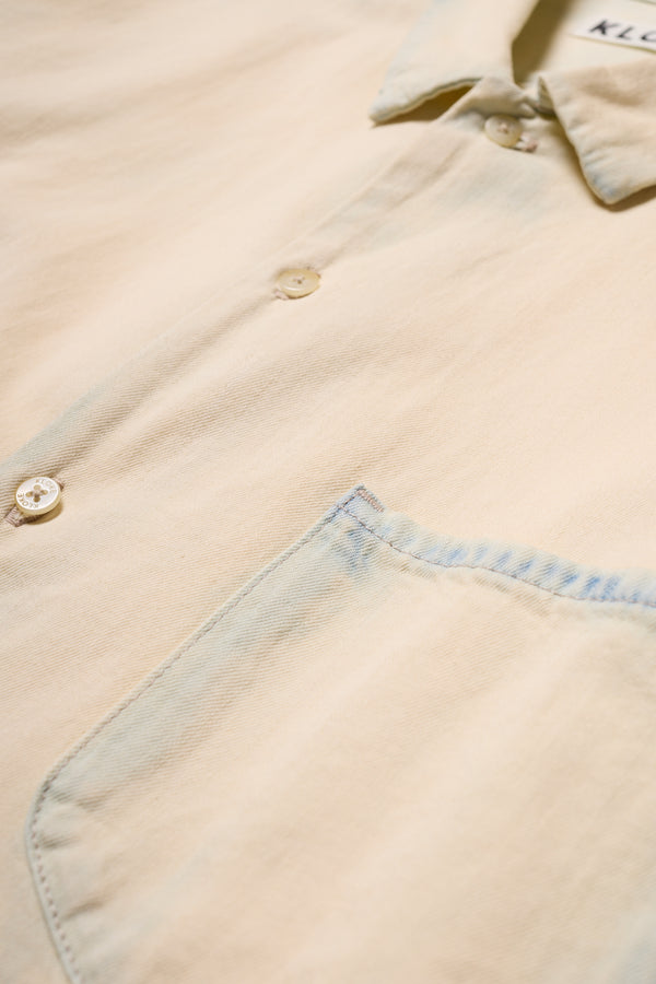 Close-up of the Mid Blue Fade with Ecru Tint Finite denim shirt chest pocket with rivets and soft washed denim texture.