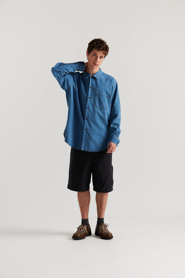 Loose long sleeve Mid-Wash denim button-up shirt, front view showing built-in collar, centre button placket, and chest patch pocket with rivet details.