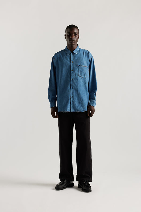 Loose long sleeve Mid-Wash denim button-up shirt, front view showing built-in collar, centre button placket, and chest patch pocket with rivet details.