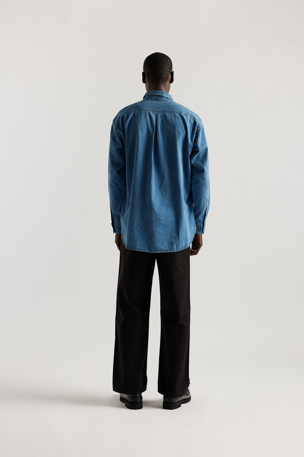 Loose long sleeve Mid-Wash denim button-up shirt, front view showing built-in collar, centre button placket, and chest patch pocket with rivet details.