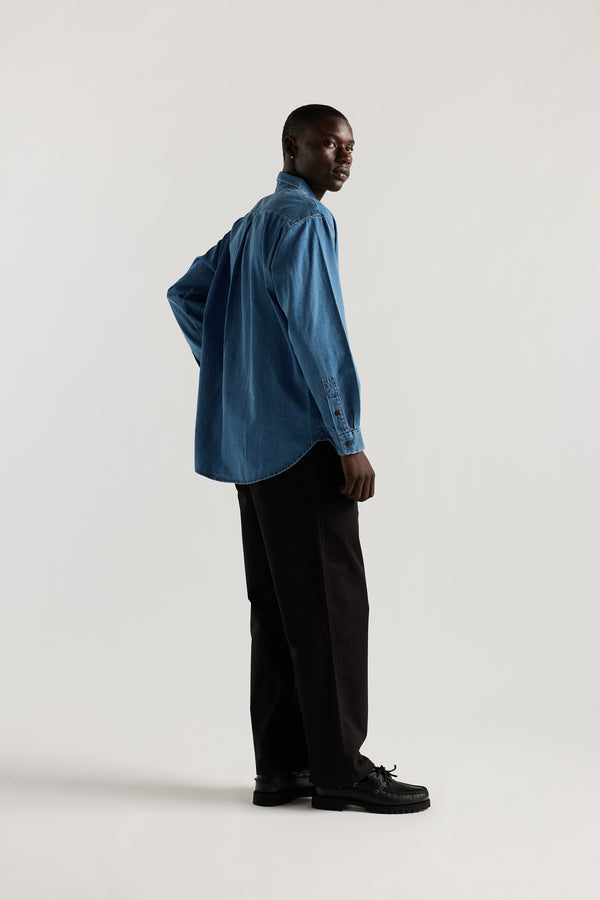 Loose long sleeve Mid-Wash denim button-up shirt, front view showing built-in collar, centre button placket, and chest patch pocket with rivet details.