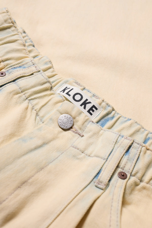 Close-up of the Mid Blue Fade with Ecru Tint Impact Denim Pant elastic waistband with Kloke signature hardware.