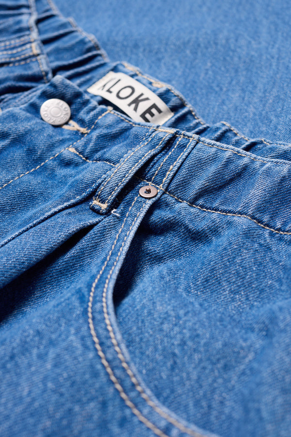 Close-up of the Mid Wash Impact Denim Pant elastic waistband with Kloke signature hardware.