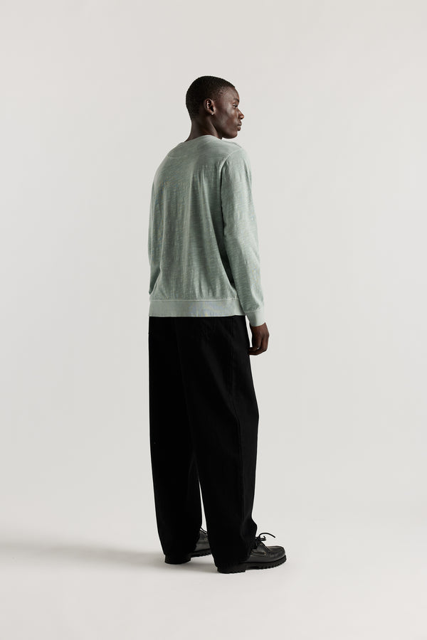 Back view of Ousmane in Black Lenz Pant with straight-leg silhouette, front patch pockets and twin-needle topstitch detail.