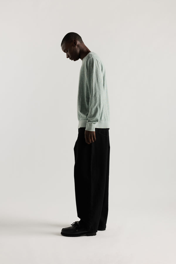 Side view of Ousmane in Black Lenz Pant with straight-leg silhouette, front patch pockets and twin-needle topstitch detail.