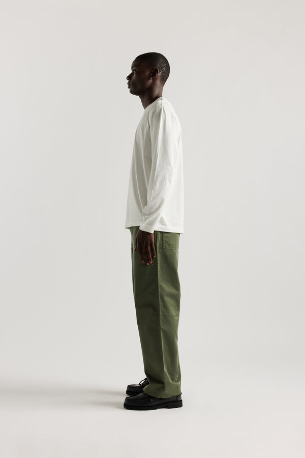 Side view of male model in Olive Lenz Pant with straight-leg silhouette, front patch pockets and twin-needle topstitch detail.