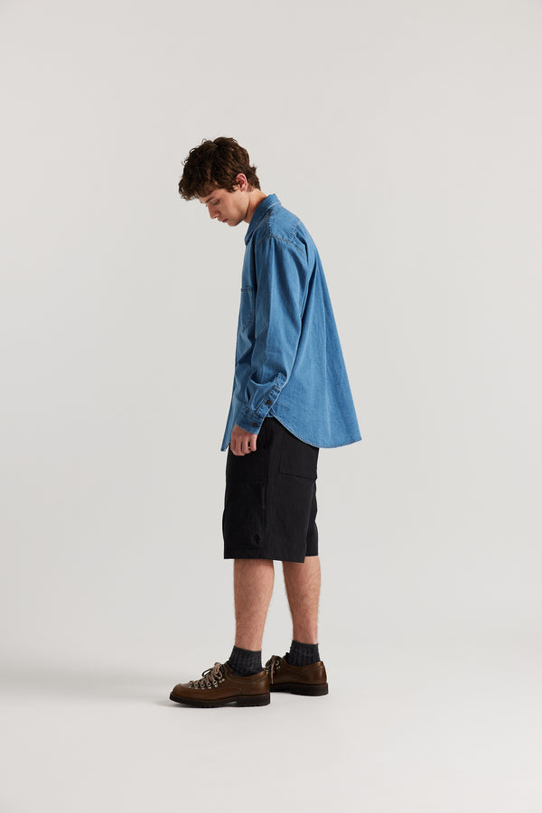 Side view of Luke in relaxed fit men’s cotton shorts in black showcasing 3D pocket construction, panel detailing, and structured laid-back design