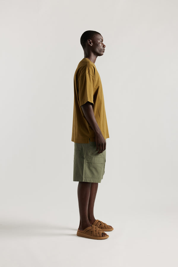 Side view of Ousmane in relaxed fit men’s cotton shorts in Olive green showcasing 3D pocket construction, panel detailing, and structured laid-back design