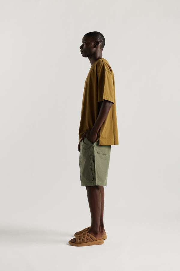 Side view of Ousmane in relaxed fit men’s cotton shorts in Olive green showcasing 3D pocket construction, panel detailing, and structured laid-back design