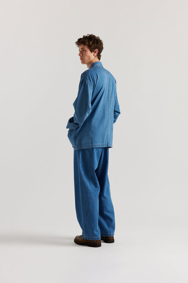 Back of male model wearing the Mid Wash Protocol Coverall in light 100% cotton denim, highlighting two-piece sleeves and flat-felled seam detailing.
