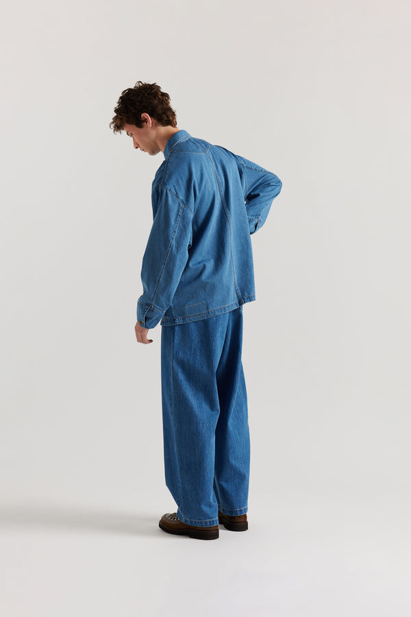 Back of male model wearing the Mid Wash Protocol Coverall in light 100% cotton denim, highlighting two-piece sleeves and flat-felled seam detailing.
