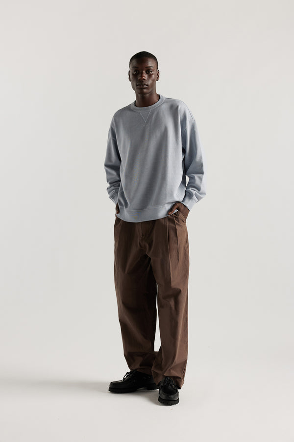 Oversized unisex French terry sweater in pigment-dyed finish, shown on model with relaxed dropped shoulders and flatlock seam detailing.