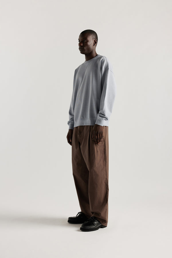 Oversized unisex French terry sweater in pigment-dyed finish, shown on model with relaxed dropped shoulders and flatlock seam detailing.
