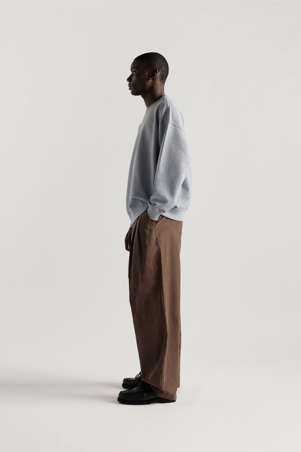 Oversized unisex French terry sweater in pigment-dyed finish, shown on model with relaxed dropped shoulders and flatlock seam detailing.
